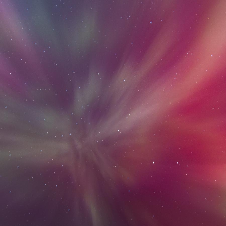 View of Aurora Borealis from directly underneath; shows the colors of pink, purple, and green.