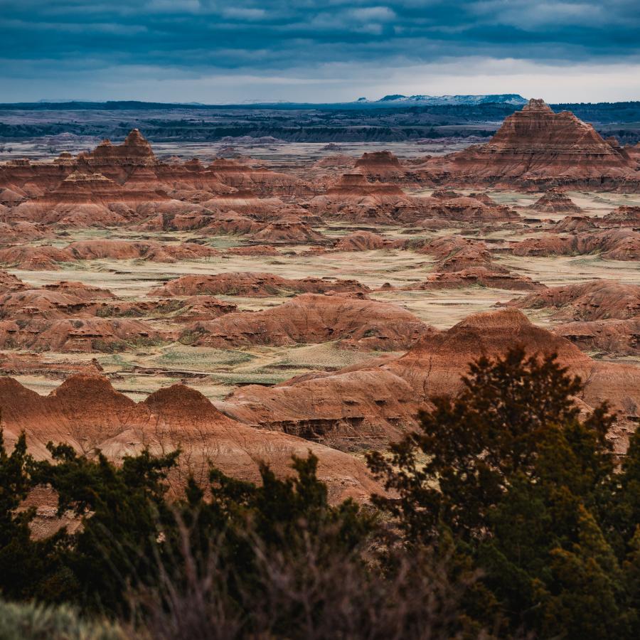 A wide shot of the Badlands in South Dakota that vividly showcases colorful variations of sediment in the peaks and and valleys of the terrain. 