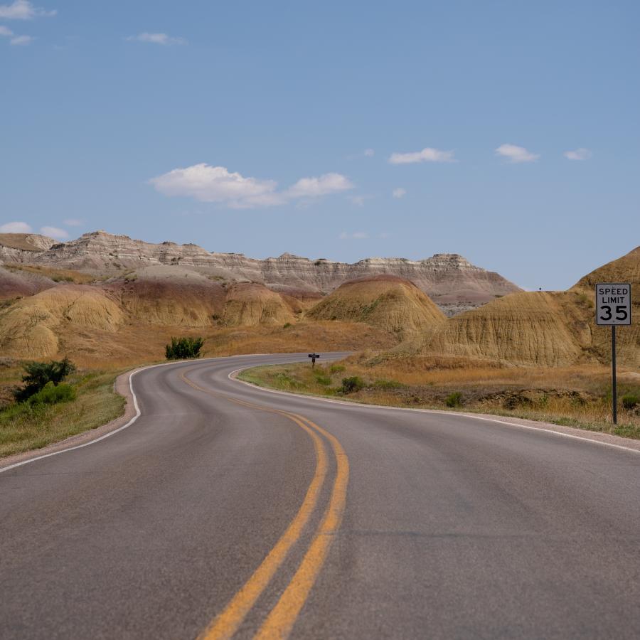 The smooth and winding road rolling through the yellow and red painted hills of the Badlands.